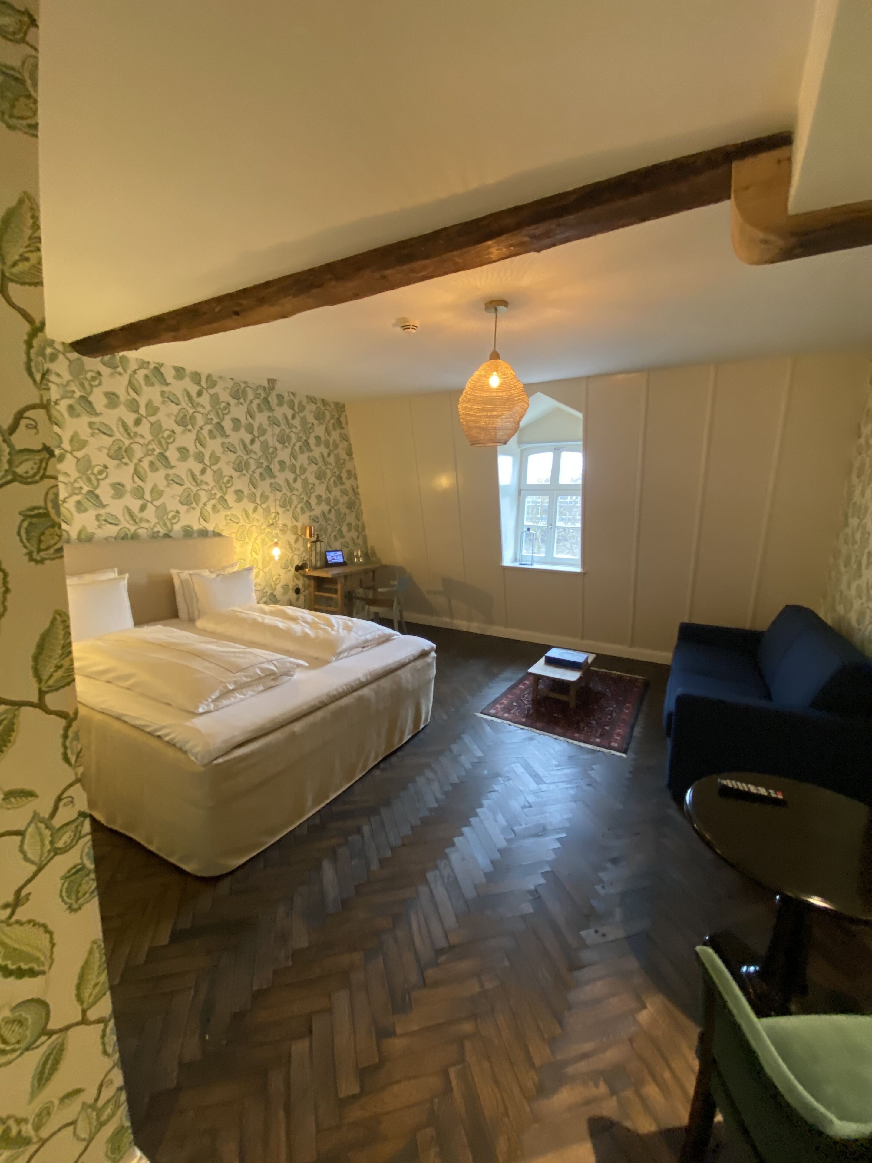 Une chambre à coucher comprenant un lit, un canapé, une petite table et un luminaire suspendu.
