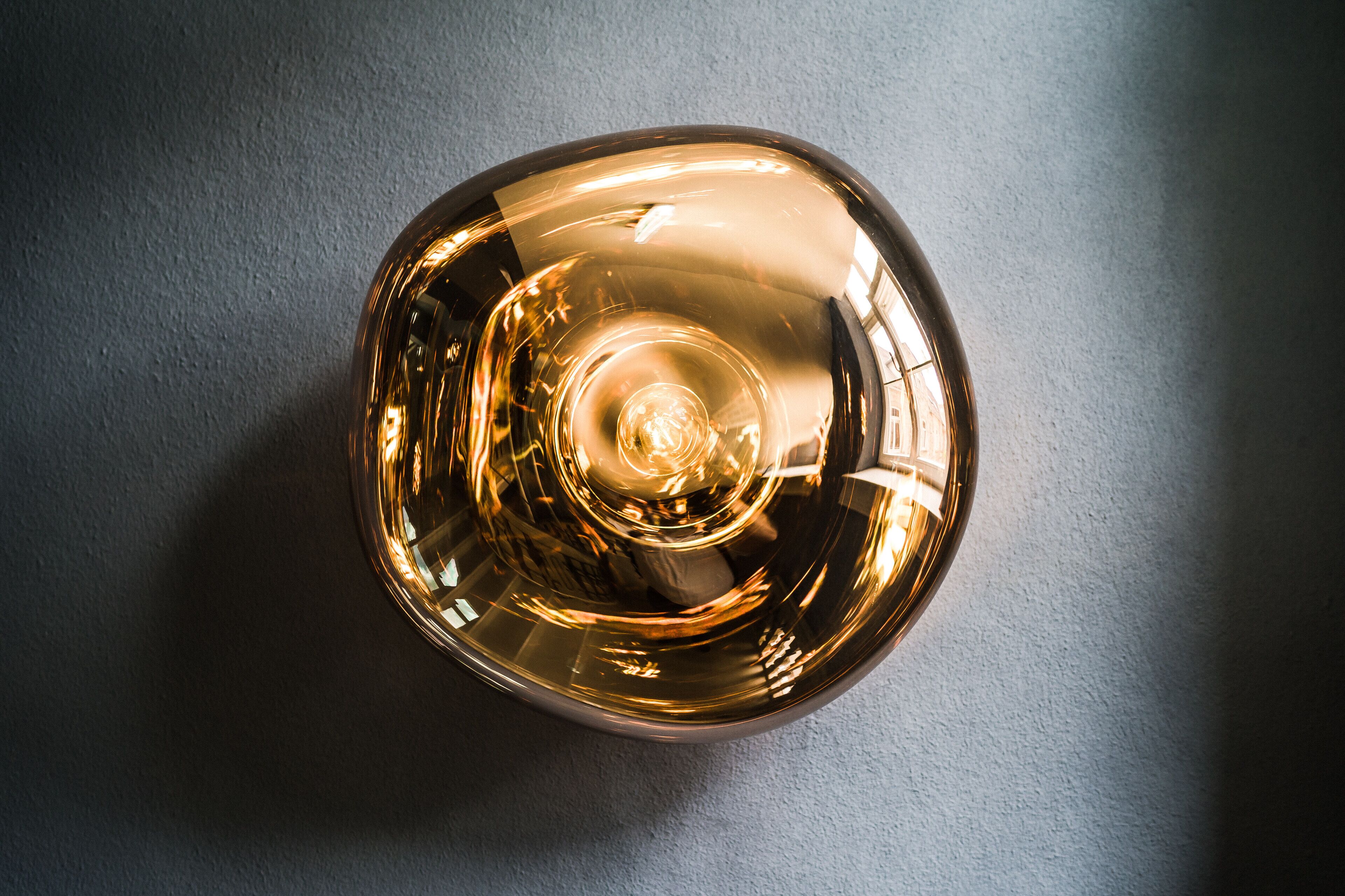A spherical, reflective object with a central light source, placed on a textured surface.