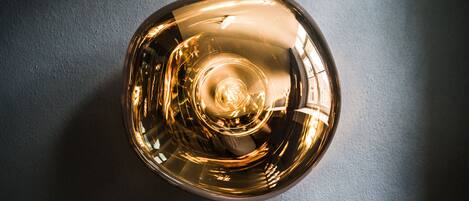 A spherical, reflective object with a central light source, placed on a textured surface.
