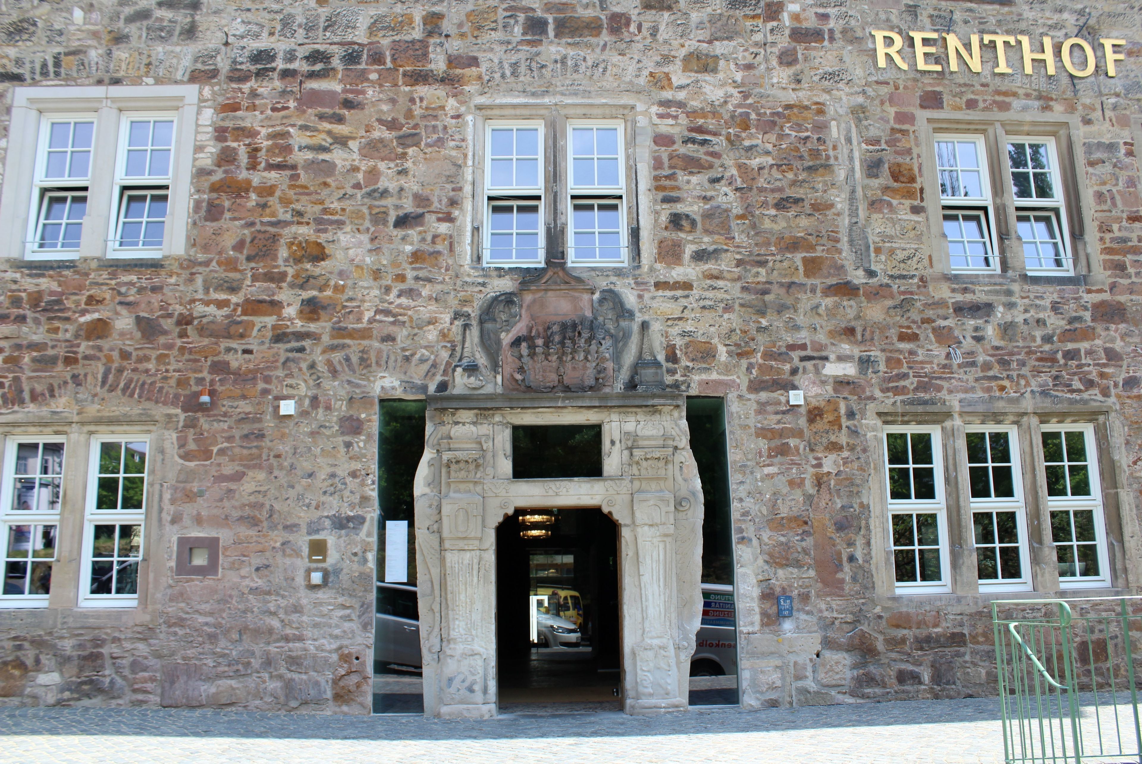 A stone building with a central entrance, multiple windows, and the name "RENHOF" above the entrance.