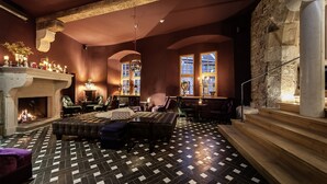 A cozy lounge area with a fireplace, comfortable seating, and a patterned floor. - Renthof Kassel (Kassel)