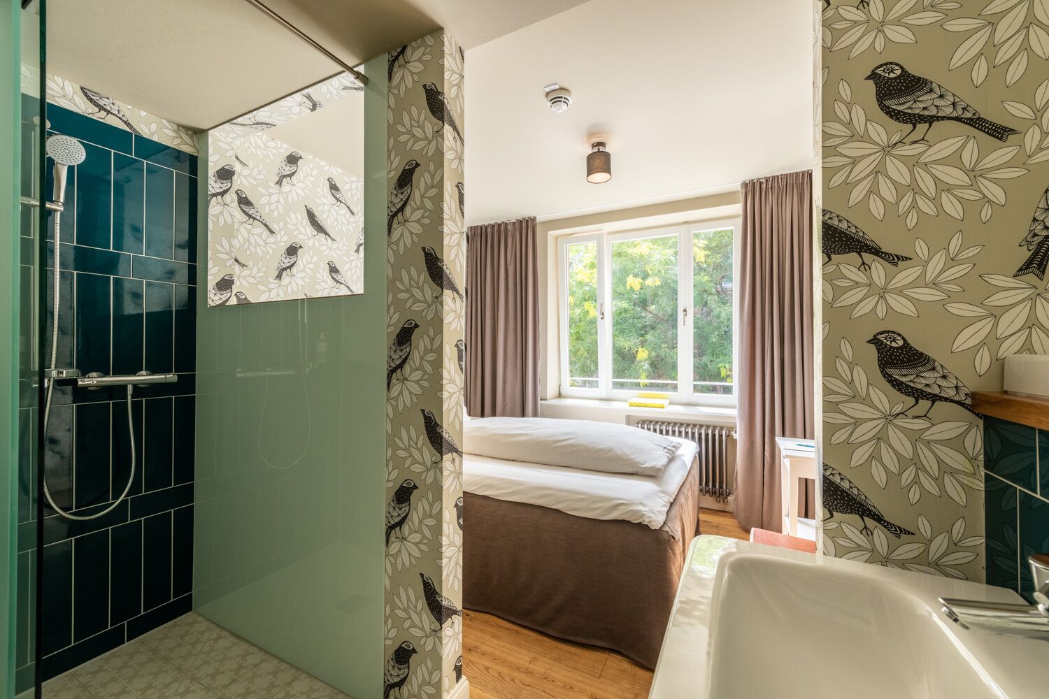 Un baño con ducha, cama y ventana con cortinas.