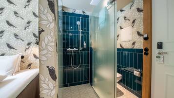 Ein Badezimmer mit Dusche, Toilette und einem Bett mit blumigem Wandpapier.