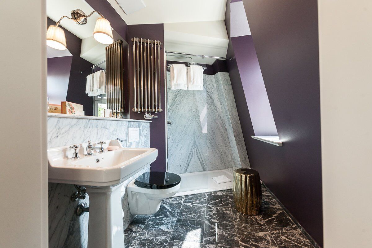 Een moderne badkamer met een marmeren wastafel, toilet en douche.