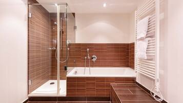 A modern bathroom with a glass-enclosed shower, a freestanding bathtub, and a built-in towel rack.