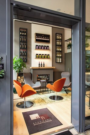 Un interior moderno con mostrador de recepción, zona de estar y exhibición de vinos.
