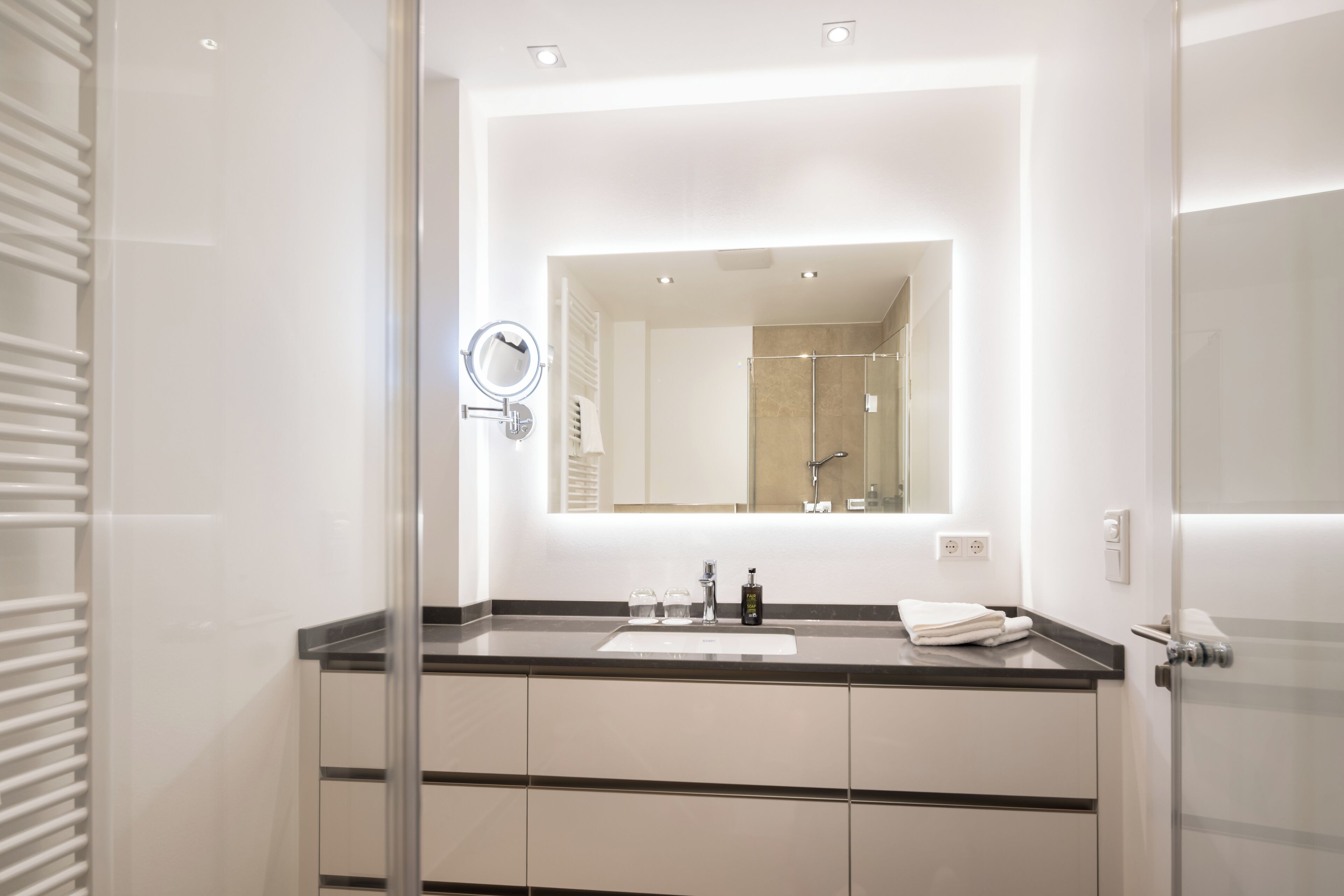Une salle de bain moderne avec un grand miroir, un lavabo et une douche à parois de verre.