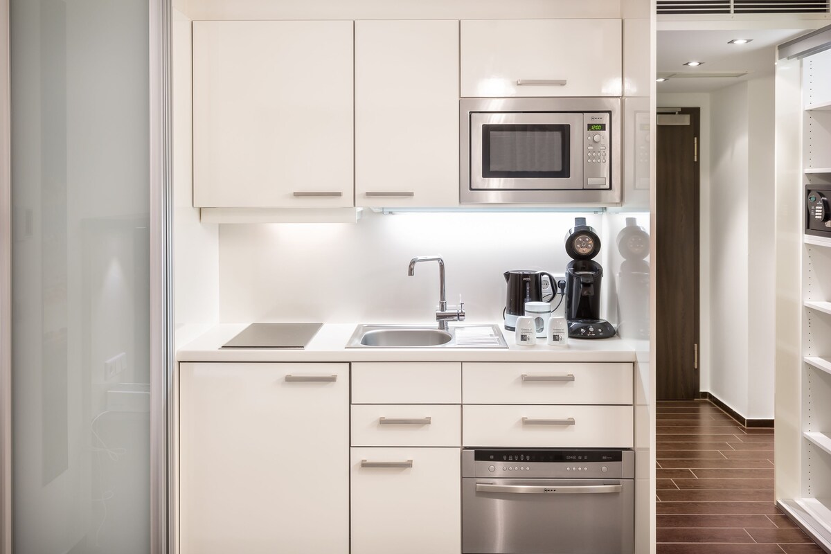 A modern kitchen with white cabinetry, a stainless steel microwave, a coffee maker, and a dishwasher.