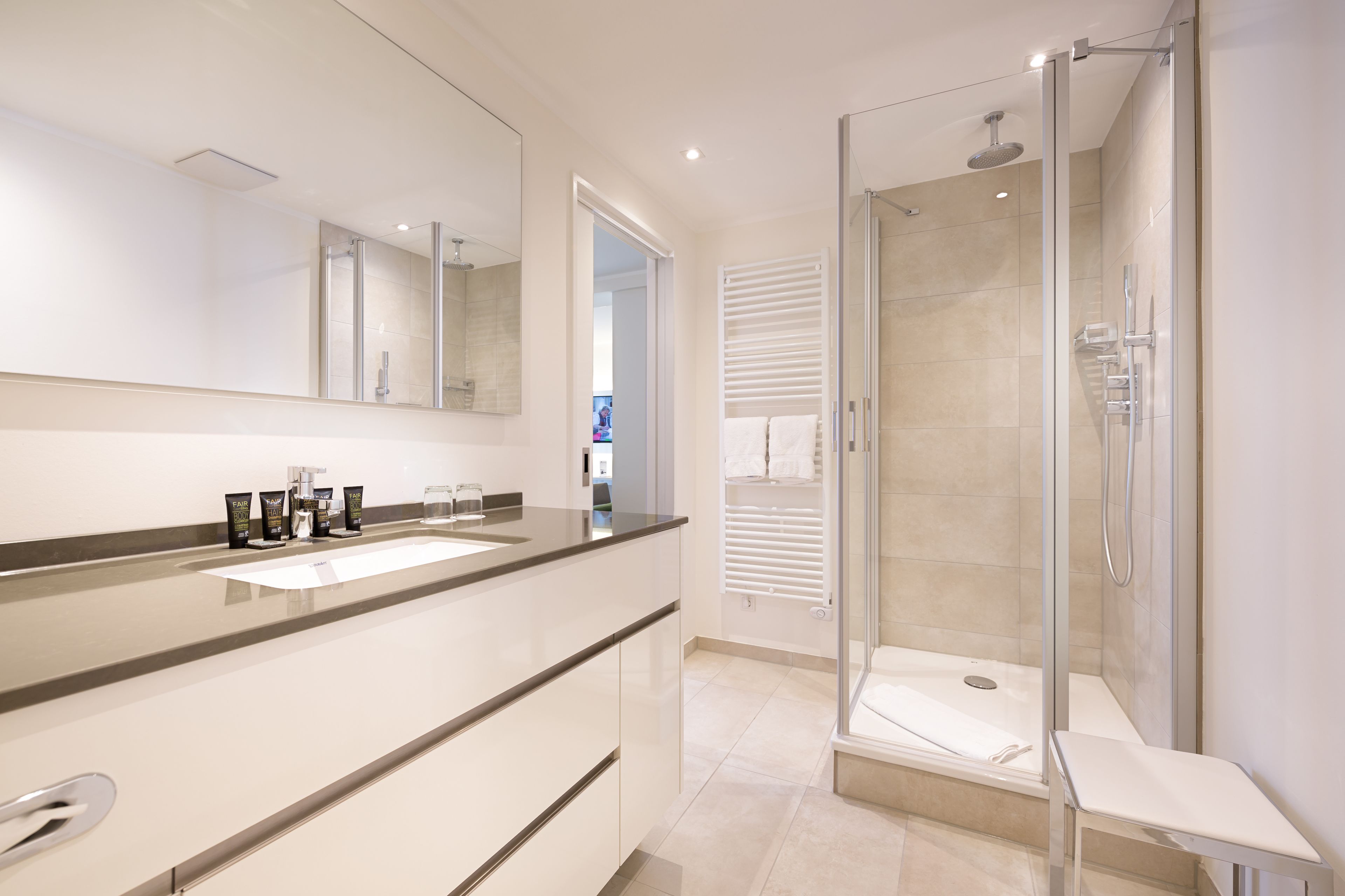 A modern bathroom with a glass-enclosed shower, a large mirror, and a vanity with a sink.