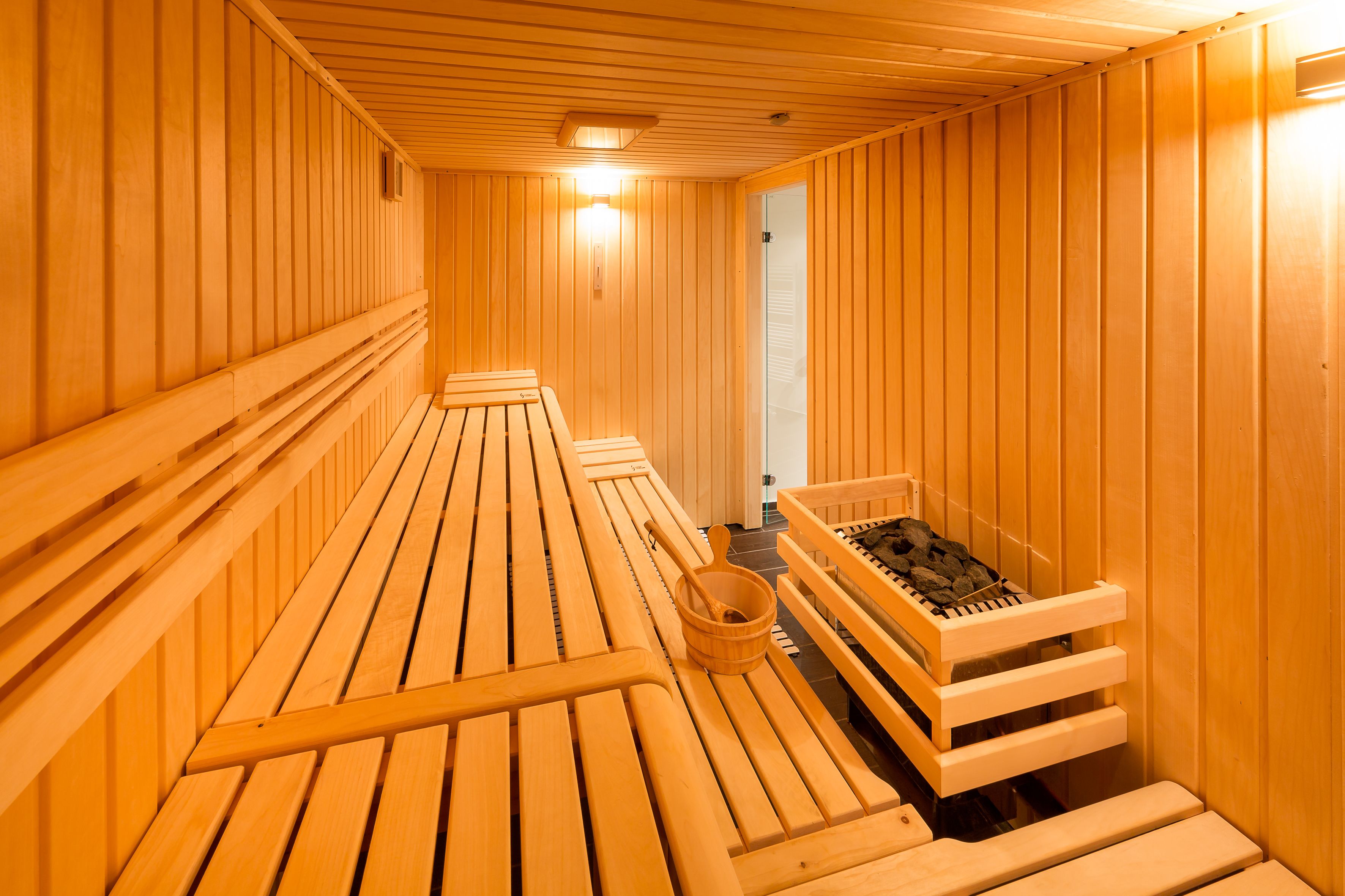 Un sauna avec des bancs en bois et un banc doté d’un siège et d’un dossier.