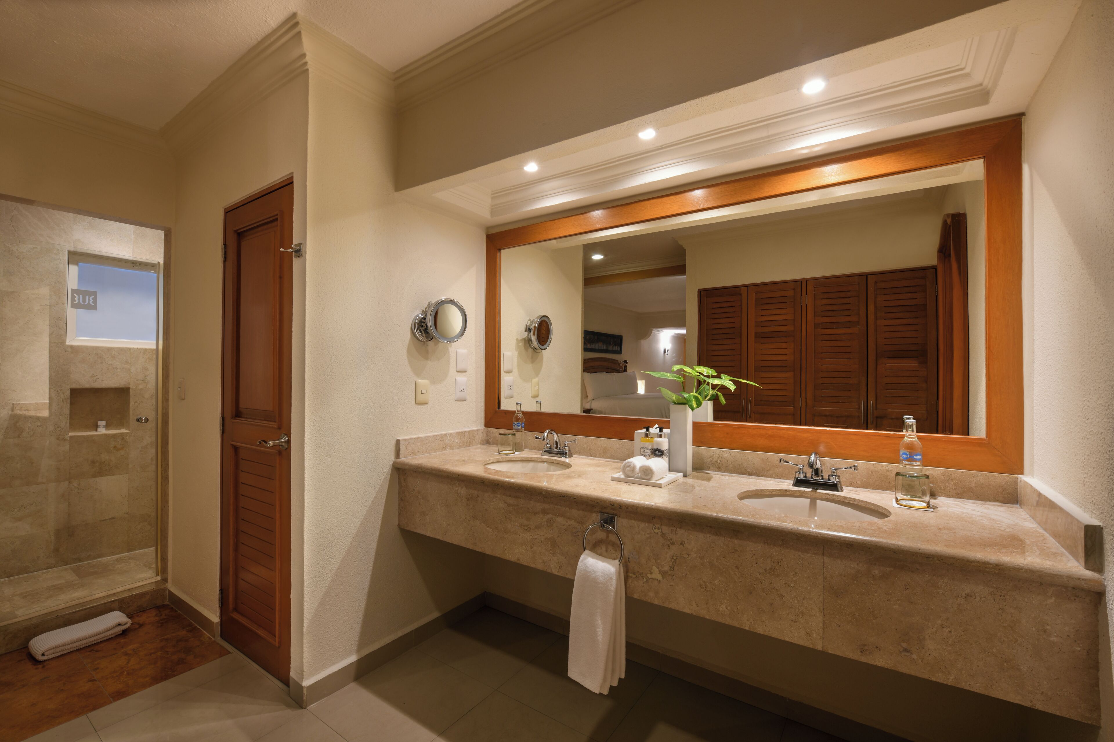 A bathroom with two sinks, a large mirror, and a shower.