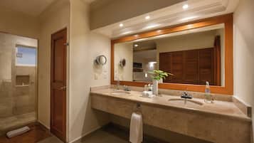 A bathroom with two sinks, a large mirror, and a shower.