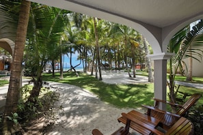 A beachside hotel with palm trees, a sandy walkway, and wooden seating areas. - El Dorado Seaside Palms, All & More Inclusive - Adults Only (Kantenah)