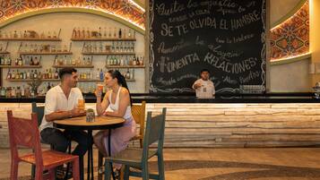 A bar with a chalkboard menu, wooden shelves with bottles, and a patterned ceiling.