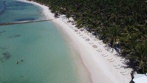 An aerial view of a beach with clear turquoise waters, white sand, and rows of sun loungers and palm trees. - El Dorado Seaside Palms, All & More Inclusive - Adults Only - All inclusive (Kantenah)