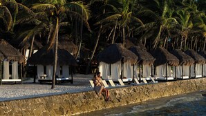 A beachside resort with thatched-roof huts, white lounge chairs, and a stone wall separating the sand from the water. - El Dorado Seaside Palms, All & More Inclusive - Adults Only - All inclusive (Kantenah)