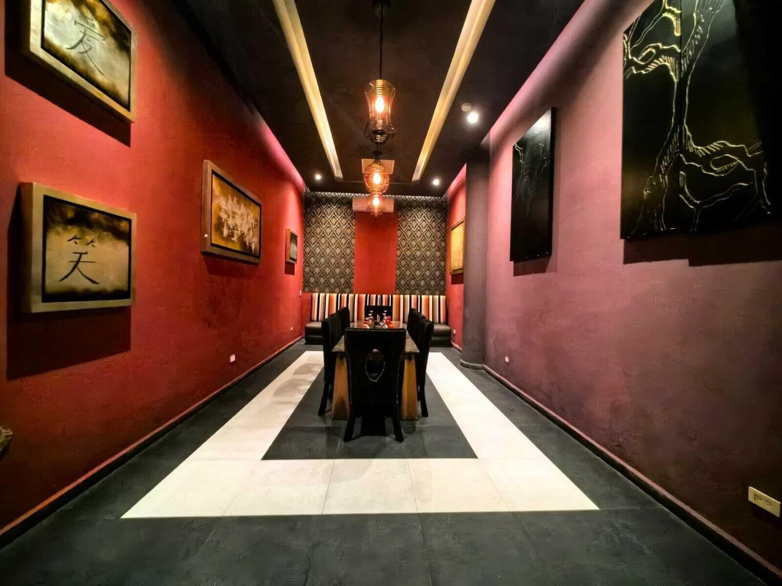 A hallway with red walls, patterned wallpaper, and a central table with chairs.