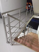 Una escalera metálica con barandilla que baja a un nivel inferior.