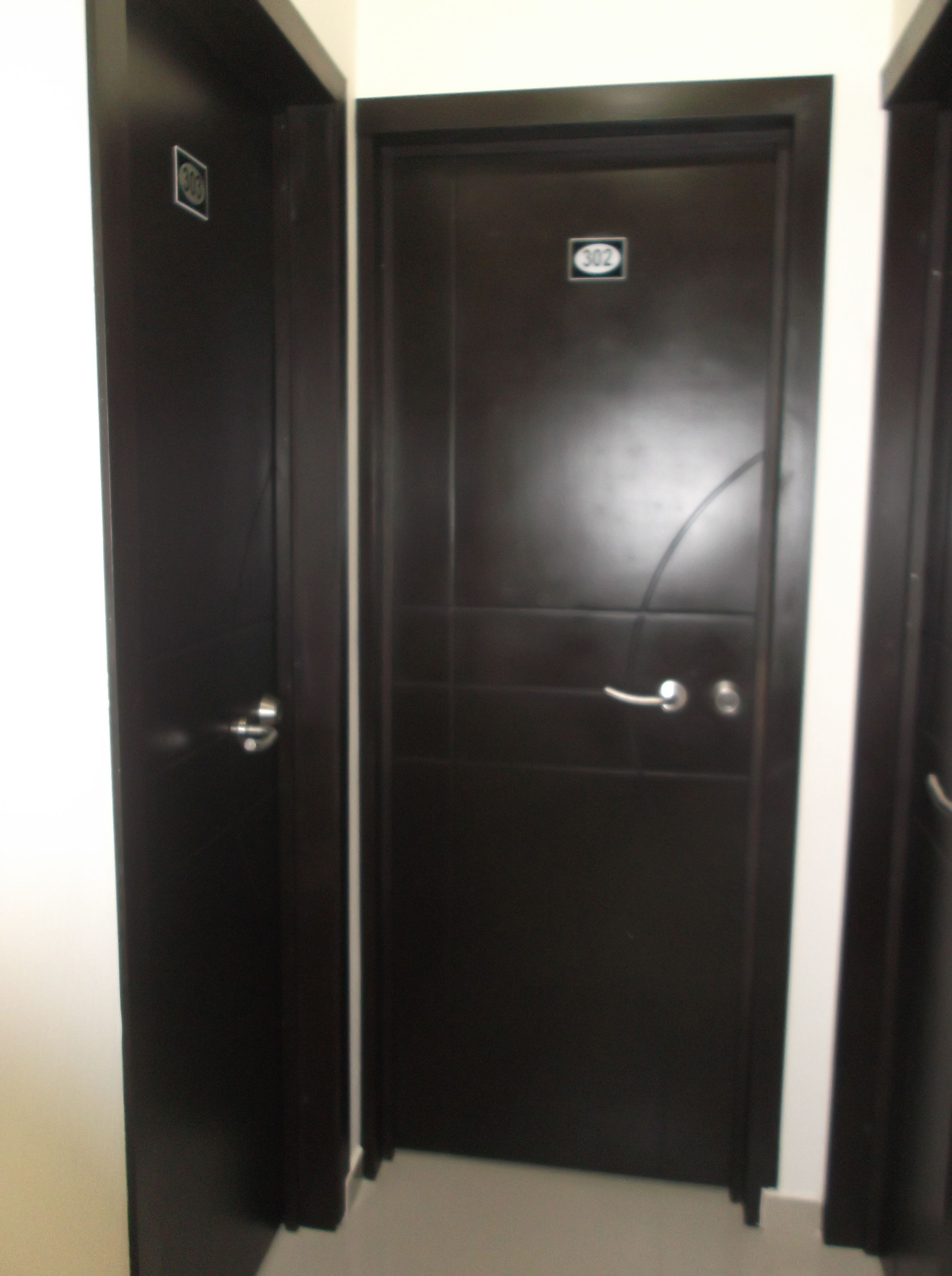 Una puerta de madera oscura cerrada, con un pequeño letrero encima y un picaporte.