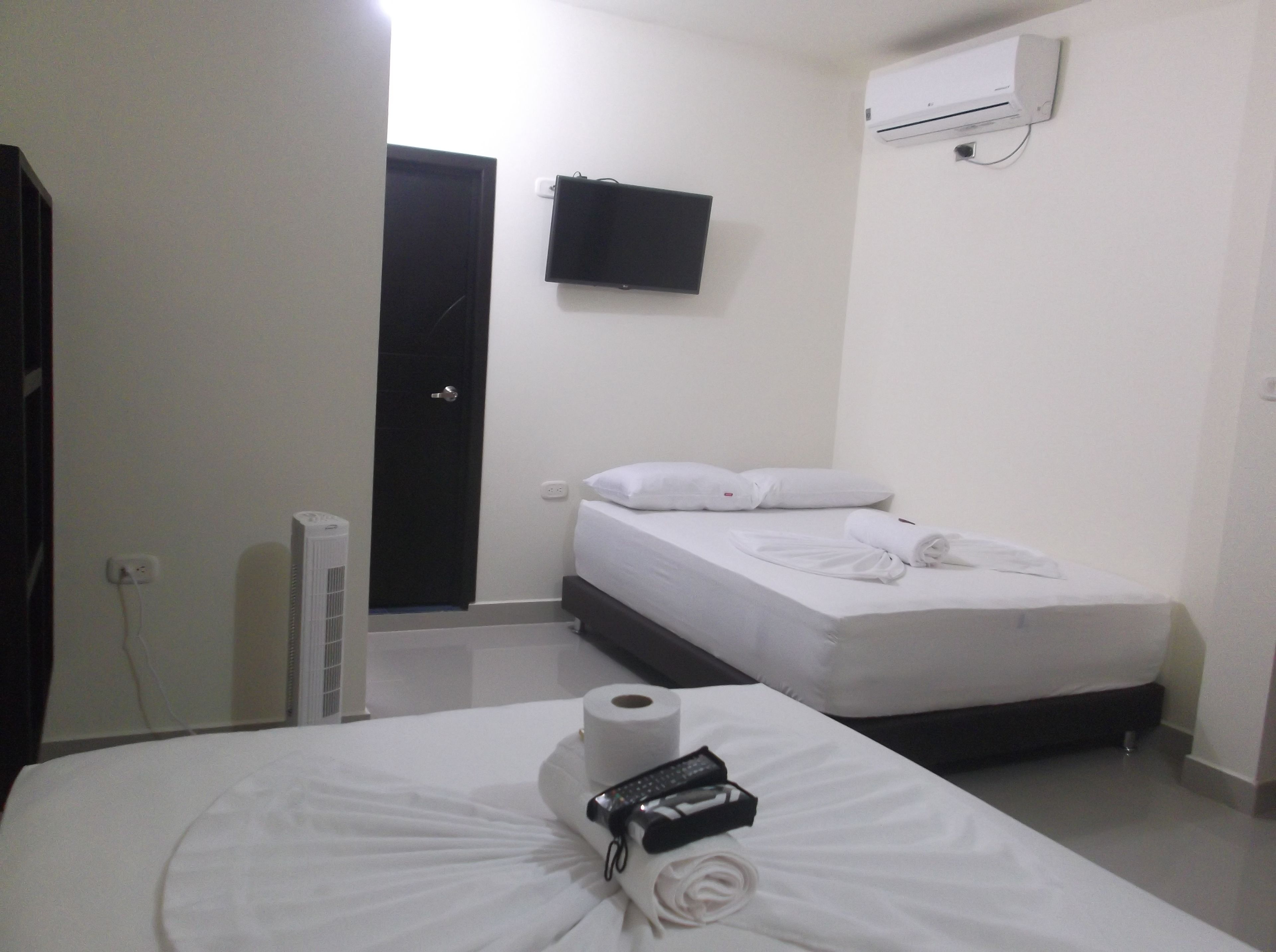 Una habitación de hotel con cama, televisión, aire acondicionado y puerta.