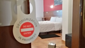 A hotel room with a bed, a nightstand, and a wall-mounted light. A sign on the door reads "DO NOT ENTER IN PROGRESS." - Hotel Cuéntame (Burgos)