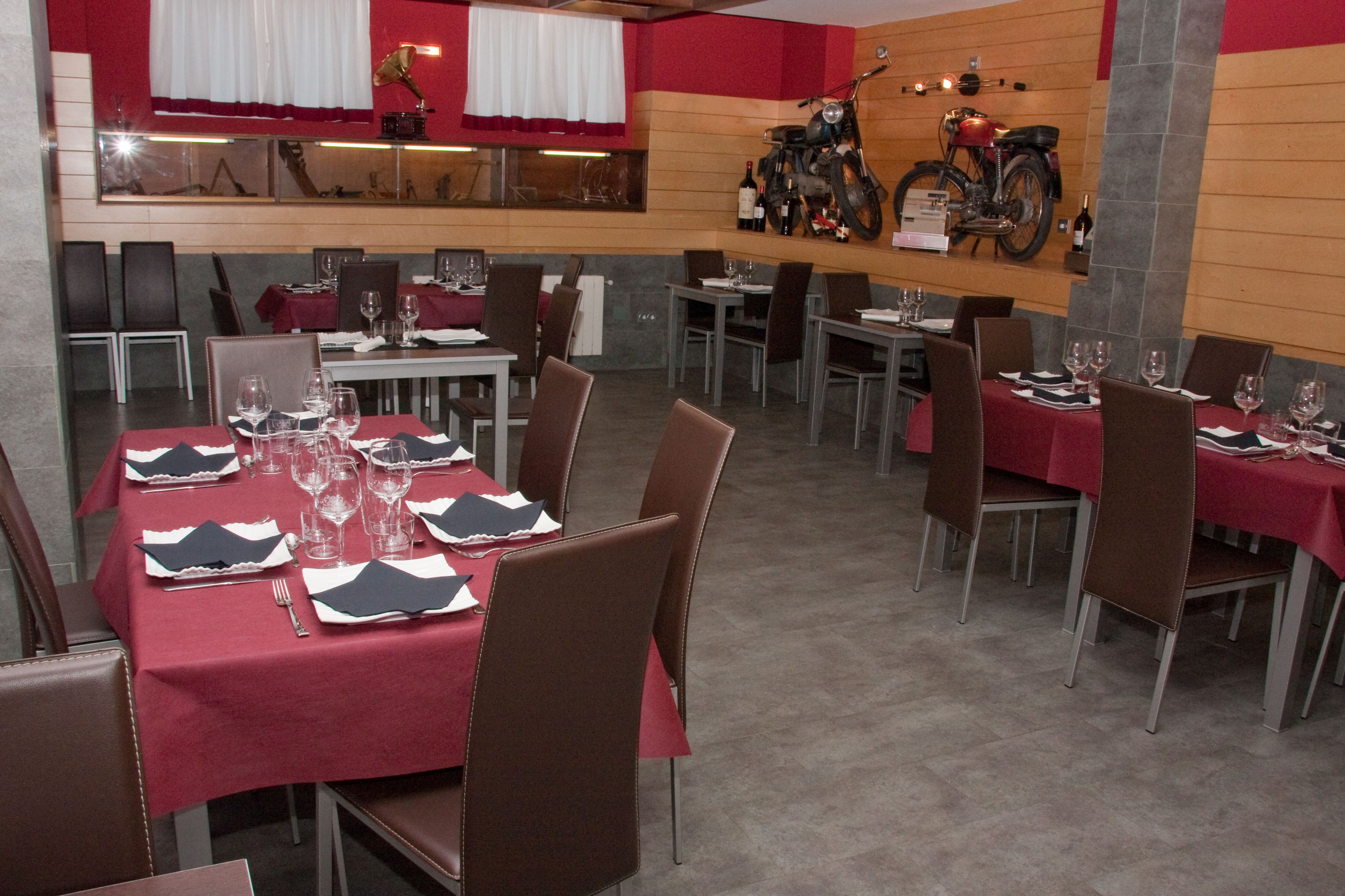 Un restaurant avec des tables dressées, des chaises et une moto accrochée au mur.