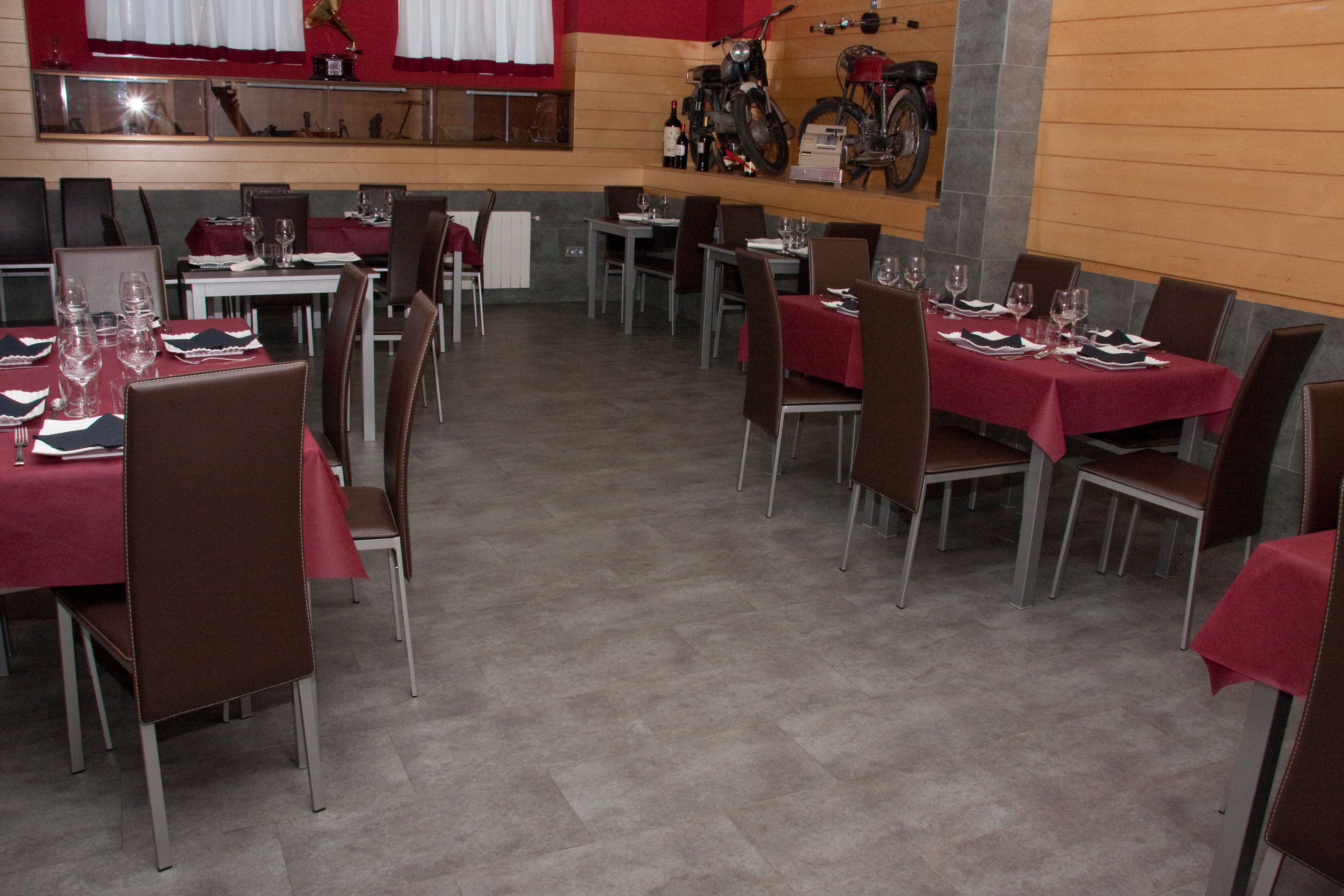 Un restaurante con mesas dispuestas para comer, sillas y una motocicleta en la pared.