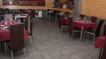 Un restaurante con mesas dispuestas para comer, sillas y una motocicleta en la pared.