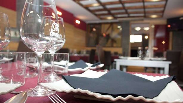 A dining table set with wine glasses, cutlery, and black napkins. - Hotel Cuéntame (Burgos)