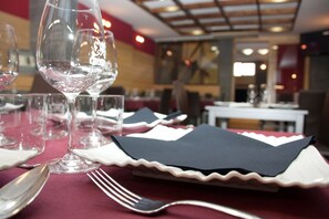 Una mesa de comedor dispuesta con copas de vino, cubiertos y servilletas negras.