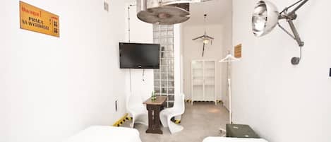 A hotel room with two beds, a flat-screen TV, a ceiling fan, and a wall-mounted lamp.
