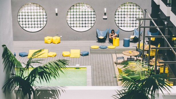 A modern outdoor lounge area with circular seating, a pool, and potted plants.