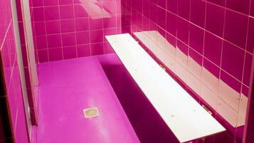 Un baño con azulejos rosas, un lavamanos blanco y un perchero para toallas.