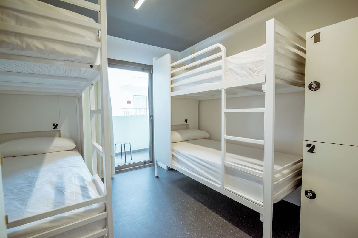Une chambre de dortoir avec des lits superposés, une porte et une vue sur l’extérieur.