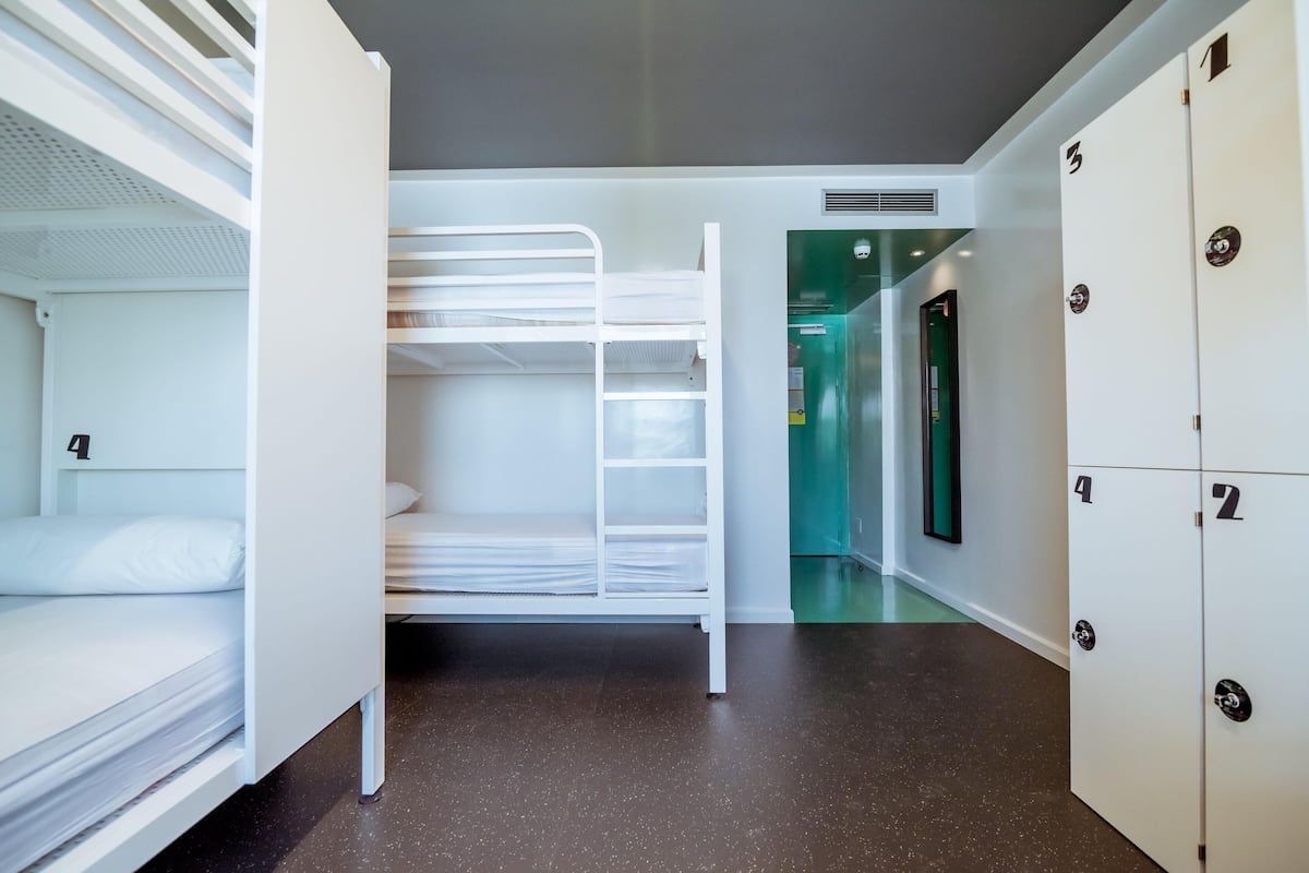 Une chambre d’hôtel avec des lits superposés, une kitchenette et une salle de bain avec douche et toilettes.