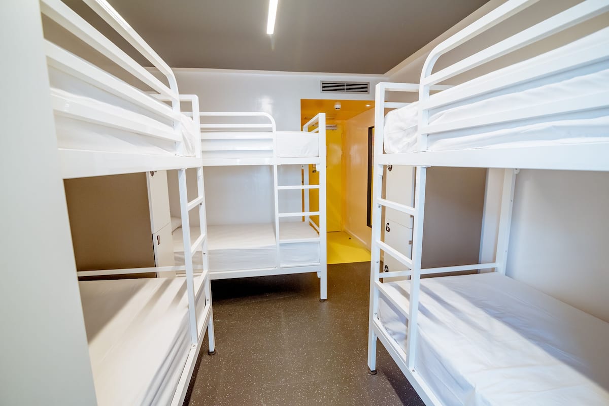 Une chambre de dortoir équipée de lits superposés, d’une porte et d’un système de ventilation.