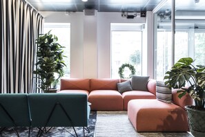 Ein modernes Wohnzimmer mit Ecksofa, türkisfarbenen Sesseln und Topfpflanzen.