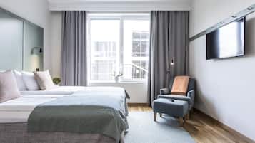 Ein modernes Schlafzimmer mit einem großen Bett, einem Sessel, einem Fernseher und einem Fenster mit Vorhängen.