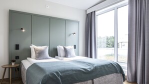 A modern bedroom with a large bed, two bedside tables, and a large window with curtains. - Biz Apartment Hammarby Sjostad (Stockholm)