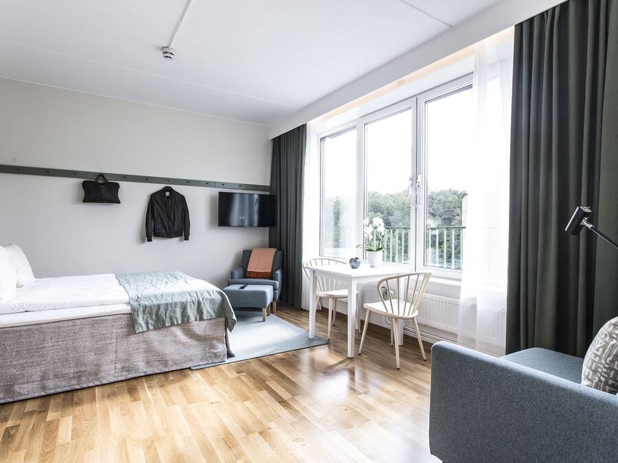 Quarto de hotel moderno com cama, escrivaninha e vista para o exterior.