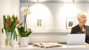 A reception desk with a laptop, a vase with flowers, and a framed picture on the wall. - Biz Apartment Hammarby Sjostad (Stockholm)