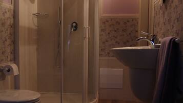 A bathroom with a shower, toilet, sink, and mirror.