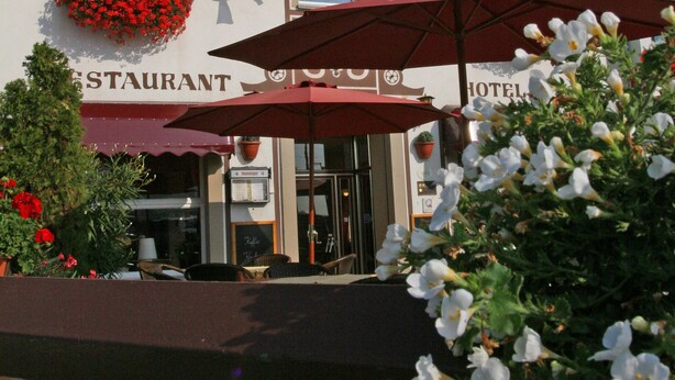 A hotel named "KRONE" with red flower boxes, flags, and outdoor umbrellas. - Hotel Krone Rüdesheim (Ruedesheim am Rhein)