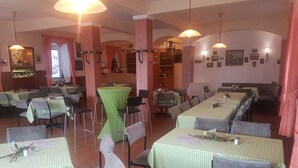 A restaurant with multiple tables covered in green checkered tablecloths, arranged in a spacious layout with high ceilings and pendant lighting. - Hotel Krone Rüdesheim (Ruedesheim am Rhein)
