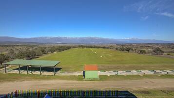 A golf course with a green field, a clubhouse, and mountains in the background.
