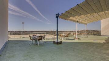 Une terrasse extérieure avec une table et des chaises, un espace abrité et une vue sur le paysage.
