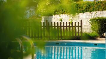 A swimming pool with a wooden fence and a stone wall in the background.