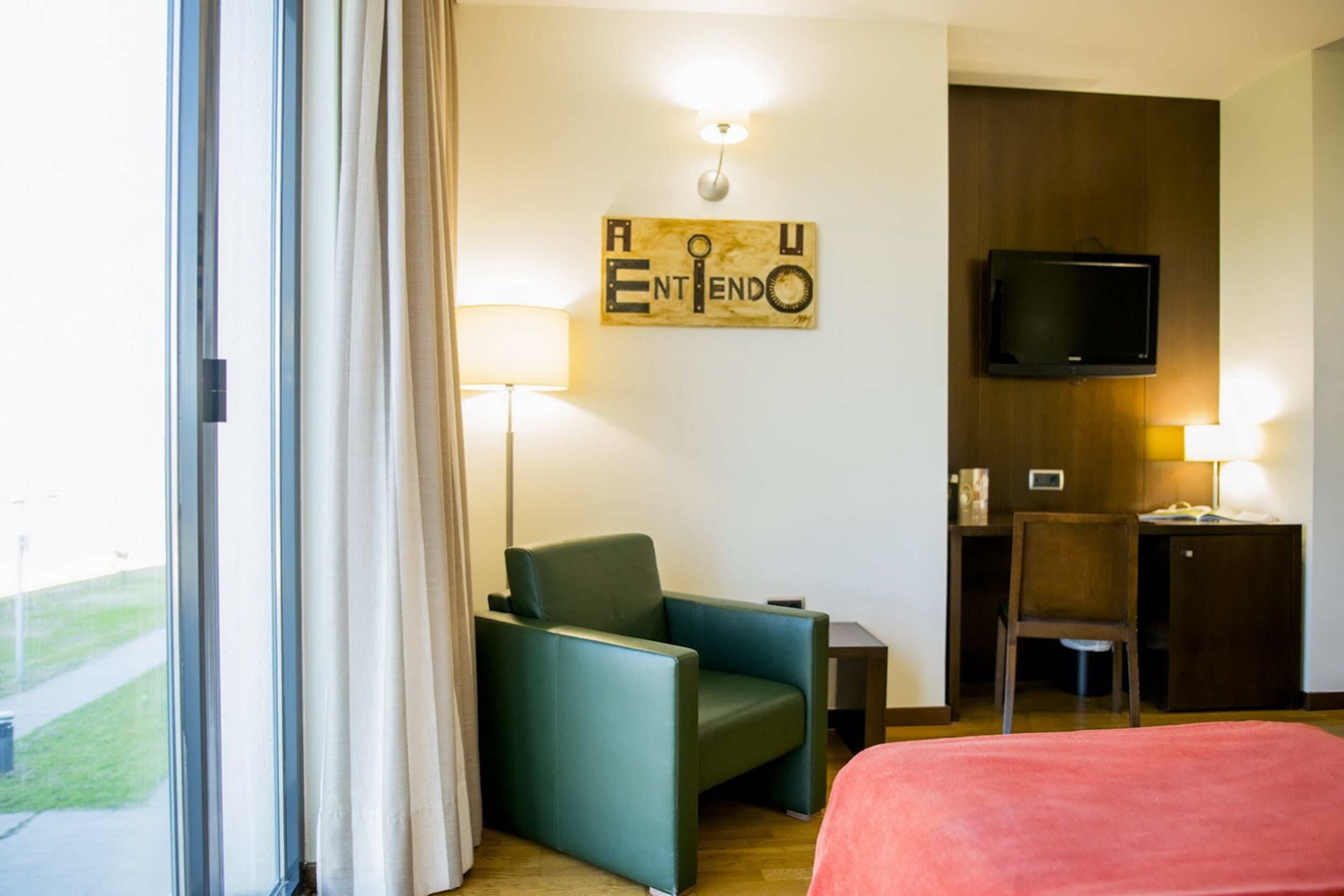 Une chambre d’hôtel équipée d’un lit, d’un bureau, d’une chaise, d’une télévision et d’une œuvre d’art accrochée au mur.