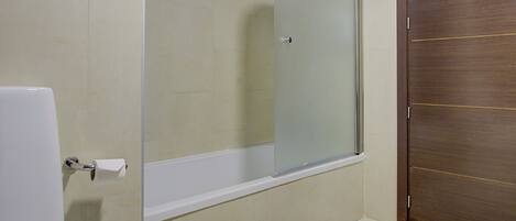 A bathroom with a toilet, a shower stall, and a wooden door.