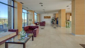 Un vestíbulo amplio con ventanas grandes, asientos cómodos y una zona de recepción.